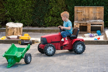Jongen op speeltractor aan het rijden